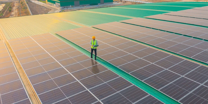 Solar Panels for Manufacturing Plants. An image of an aerial top view of a male engineer with solar panels on the roof in factory industry.